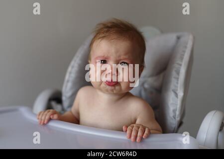 Weinendes Baby Mädchen auf ihrem Hochstuhl sitzend Stockfoto