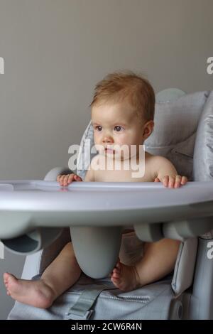 Weinendes Baby Mädchen auf ihrem Hochstuhl sitzend Stockfoto