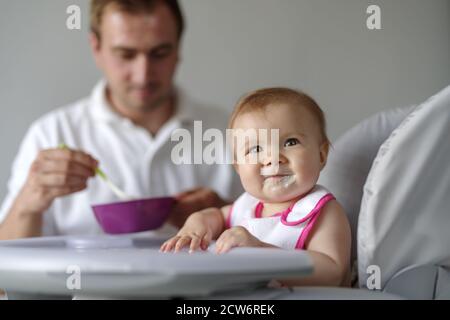 Vater Fütterung Baby Tochter mit Löffel im Hochstuhl Stockfoto