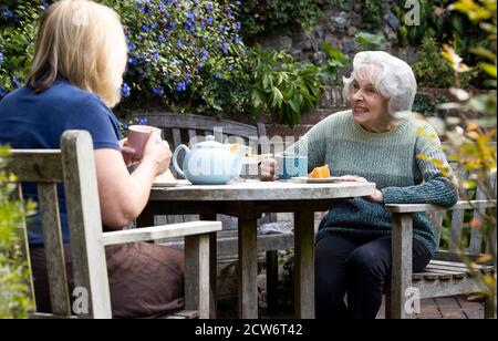 Ältere Frau Besucht Einsame Ältere Mutter Im Garten Während Der Sperre Stockfoto