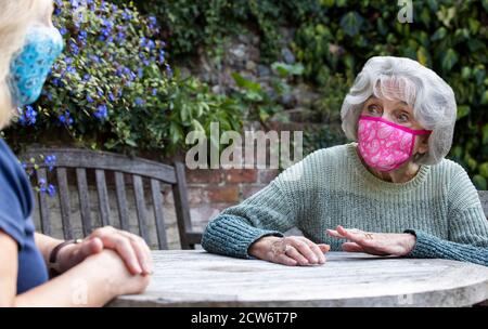 Reife Frau Trägt Maske Besuch Einsam Senior Mutter Im Garten Während Der Sperrung Stockfoto