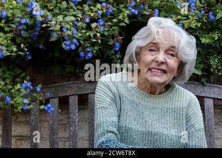 Porträt Einer Lächelnden Älteren Frau, Die Sich Im Garten Zu Hause Entspannt Stockfoto