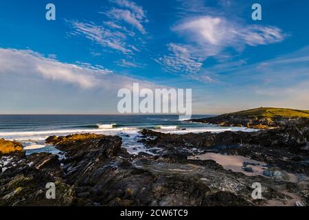 Krachende Wellen bei Sonnenaufgang in der Nähe von Fistral Beach mit Blick auf Towan Head, Newquay, Cornwall, Großbritannien Stockfoto