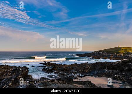 Krachende Wellen bei Sonnenaufgang in der Nähe von Fistral Beach mit Blick auf Towan Head, Newquay, Cornwall, Großbritannien Stockfoto