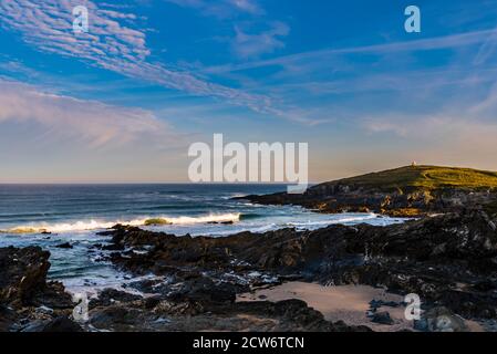 Krachende Wellen bei Sonnenaufgang in der Nähe von Fistral Beach mit Blick auf Towan Head, Newquay, Cornwall, Großbritannien Stockfoto