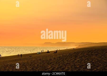 Fischer am Strand bei Sonnenuntergang in West Bexington, einem Dorf im Südwesten von Dorset, England, gelegen hinter Chesil Beach in der Nähe von Bridport Stockfoto