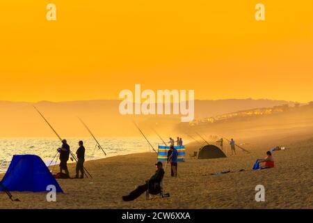 Fischer am Strand bei Sonnenuntergang in West Bexington, einem Dorf im Südwesten von Dorset, England, gelegen hinter Chesil Beach in der Nähe von Bridport Stockfoto