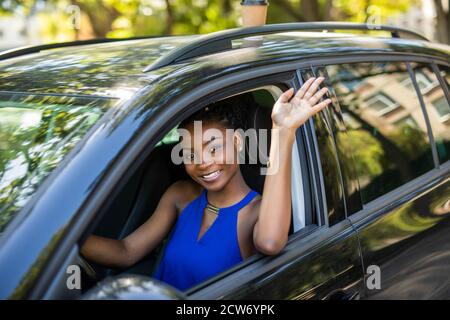 Junge Schönheit afrikanische Frau Gruß jemand während Auto fahren Die Straße Stockfoto