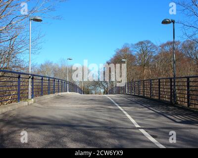 Eine leere, kurvige Fußgänger- und Fahrradstraße. Es ist eine Brücke mit Laternenpfosten auf beiden Seiten. Stockfoto