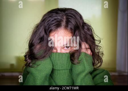 Frau versteckt ihr Gesicht im Kragen eines dicken Wollpullover Stockfoto