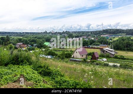 Im Hochsommer. Hütten, grüne Bäume und ein Tempel am Horizont. Blick vom Hügel. Provinzstadt Borowsk in Russland. Stockfoto