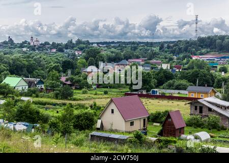 Im Hochsommer. Hütten, grüne Bäume und ein Tempel am Horizont. Blick vom Hügel. Nahaufnahme. Provinzstadt Borowsk in Russland. Stockfoto