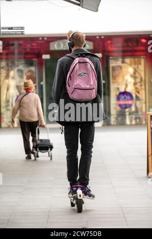 LONDON - 12. SEPTEMBER 2020: Mann mit pinkem Rucksack fährt Elektroroller durch ein Einkaufszentrum Stockfoto