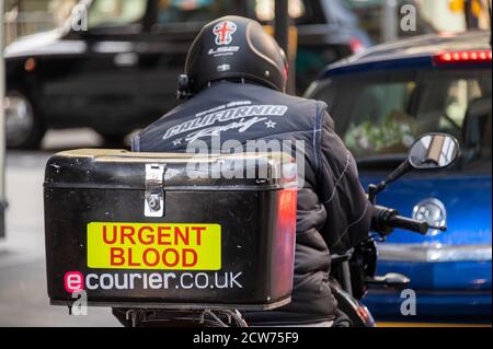 LONDON - 12. SEPTEMBER 2020: Motorrad-Kurier im Verkehr mit dringendem Blut auf seinem Frachtkasten geschrieben Stockfoto