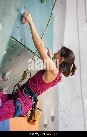 Junge Frau geschickte Kletterin an der Kletterwand Stockfoto