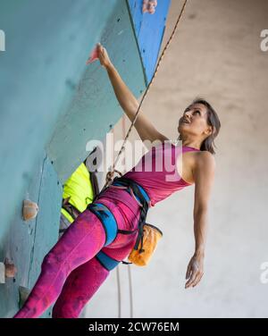 Junge Frau geschickte Kletterin ruht auf der Kletterwand Stockfoto