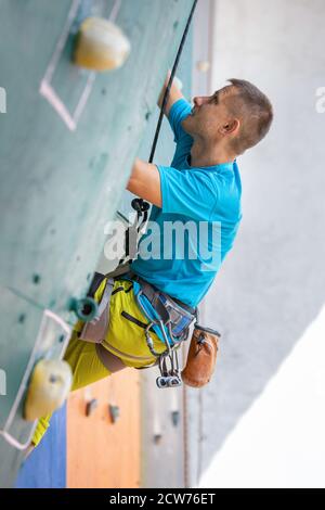 Junger Mann Kletterer an der Trainingskletterwand Stockfoto