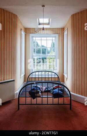 Ein altes eisernes Bett in einem leeren Zimmer in einem verlassenen Haus, Großbritannien Stockfoto