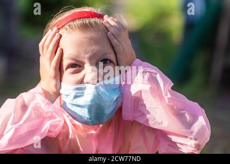 Porträt eines verängstigten Mädchens in Schutzanzug und medizinischer Maske im Sommer auf der Straße. Prävention von Coronavirus und Covid-19 während einer Pandemi Stockfoto