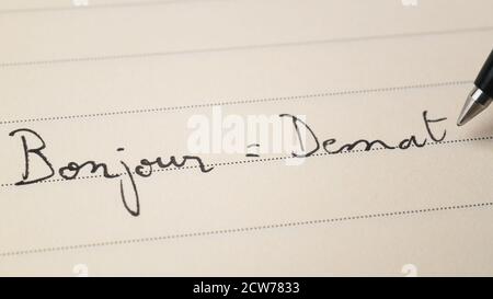 Anfänger bretonische Sprache Lernender Schreiben Hallo Wort Bonjour auf Französisch Und Demat in Breton für Hausaufgaben auf einem Notebook-Makro Aufnahme Stockfoto
