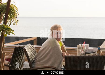 Glückliche hoffnungsvolle Frau, die den Sonnenuntergang am Meer betrachtet. Silhouette einer träumenden Frau, die hoffnungsvoll am Horizont schaut Stockfoto