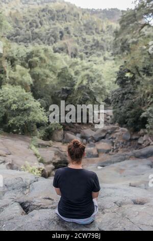 Mädchen sitzt auf einem Stein im Wald. Hochwertige Foto Stockfoto