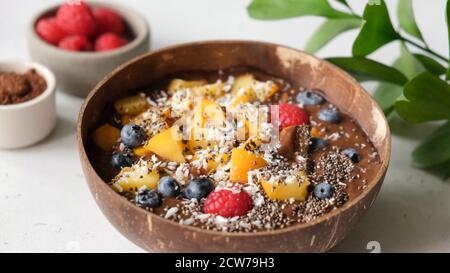 Superfood Schokolade Smoothie Schüssel mit verschiedenen Toppings Mango, Samen und Beeren Stockfoto