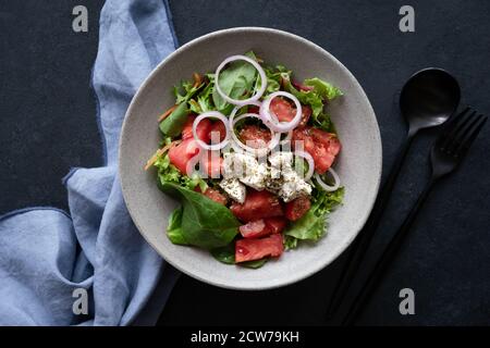 Griechischer Salat in Schüssel auf schwarzem Hintergrund, Tischansicht. Gesunder Gemüsesalat mit Feta-Käse Stockfoto