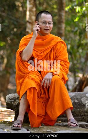 Ein buddhistischer Mönch in Safranroben, der ein Telefongespräch führt. Stockfoto