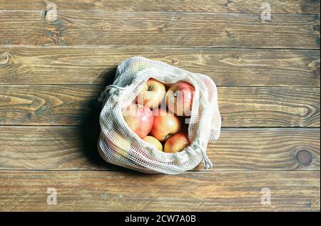 Bio-Äpfel in wiederverwendbarer umweltfreundlicher Netztasche auf dem Holzhintergrund. Paketfreies Einkaufen von Lebensmitteln. Zero Waste Konzept, Kunststoff frei Lebensstil. Reu Stockfoto