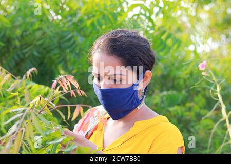 Indische junge Frau trägt Hause gemacht blaue Gesichtsmaske Prävention Während der corona Zeit sammeln neem Blätter Informationen Stockfoto