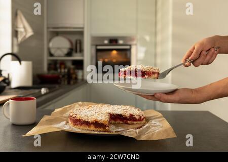 Ein Mann hält hausgemachten Pflaumenkuchen in den Händen. Ein Mann hat Frühstück mit frischem Gebäck zu Hause in der Küche. Stockfoto