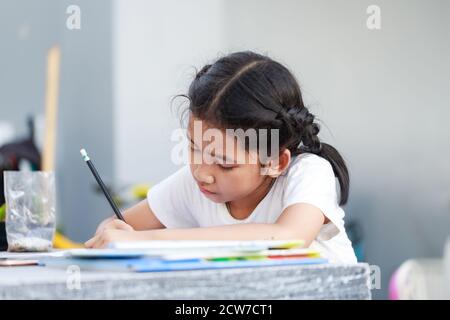 Kleine asiatische Mädchen tun Hausaufgaben mit Konzentration, wählen Sie Fokus flache Tiefe des Feldes Stockfoto