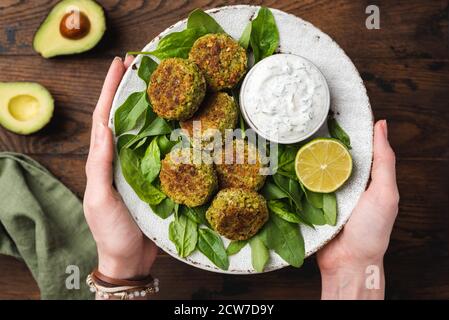 Vegetarische Kichererbsenfalafel mit Tzatziki-Sauce in weiblichen Händen. Gesunde Ernährung, saubere Ernährung, grüne Diät-Konzept Stockfoto