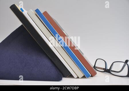 Bücher im Regal mit Unterstützung auf blauen Filz Pyramide organisiert Seitenansicht mit weißem Hintergrund Stockfoto