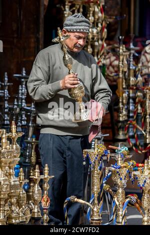 Ein Ladenbesitzer im Khan el Khal'ili Bazaar in Kairo, Ägypten reinigt eine seiner Wasserpfeifen auf dem Display. Die Wasserleitung ist immer noch häufig in Ägypten verwendet. Stockfoto