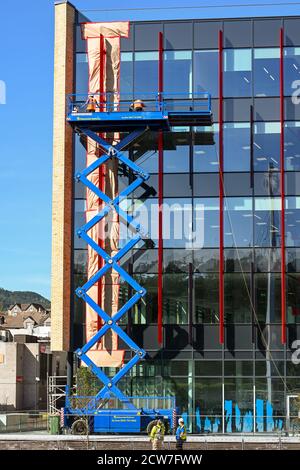 Pontypridd, Wales - September 2020: Menschen, die an einer hydraulischen Scherenhubbühne an der Außenseite einer neuen Büroanlage in Pontypridd arbeiten. Stockfoto