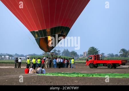 Eine Flamme brennt, während sich ein Heißluftballon für den Start bei Sonnenaufgang in Luxor in Ägypten vorbereitet. Der Ballon wird dann über den Nil und antike Stätten fliegen Stockfoto