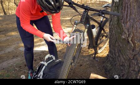 Junge kaukasische Frau Athlet touristischen Radfahrer verwendet ein Handwerkzeug, eine Fahrradpumpe, um Luft in ein Reifenrad Mountainbike aufzublasen. Panne und schnell Stockfoto