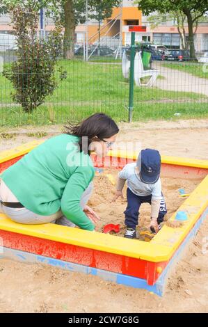 POZNAN, POLEN - 14. Mai 2016: Unbekannte Frau und Kind spielen an einem sonnigen Tag in einer Sandkiste auf einem Spielplatz Stockfoto