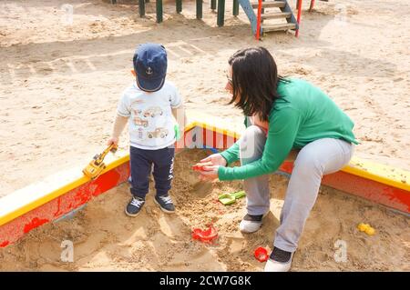 POZNAN, POLEN - 14. Mai 2016: Unbekannte Frau und Kind spielen an einem sonnigen Tag in einer Sandkiste auf einem Spielplatz Stockfoto