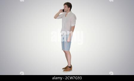 Glücklicher junger Mann, der sich mit dem Handy unterhielt und lächelte Verlauf Stockfoto