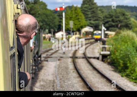 GLOUCESTERSHIRE, ENGLAND - SEPTEMBER 2019: Eisenbahnenthusiasten lehnen sich aus dem Fenster eines Zuges auf der Gloucestershire und Warwickshire Railway. Stockfoto