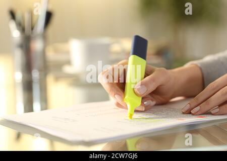 Nahaufnahme einer Frauenhand, die Text auf dem Dokument unterstreicht Mit Marker auf dem Schreibtisch zu Hause Stockfoto