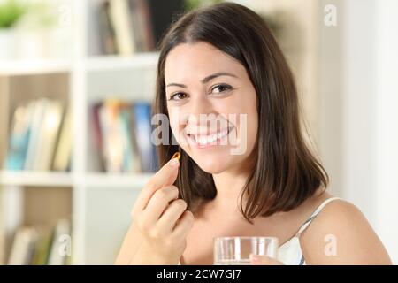 Glückliche Frau, die Vitamin Pille isst, sieht Sie stehen an Zu Hause Stockfoto