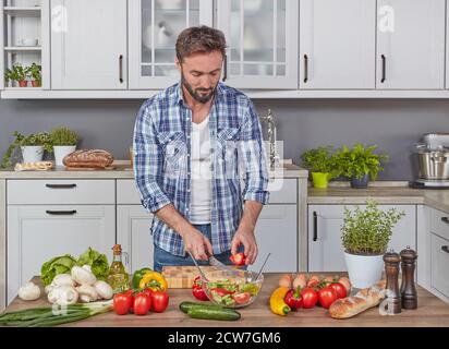 Hübscher Mann, der Gemüse in der Küche schneidet Stockfoto