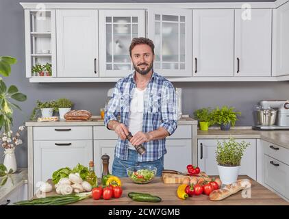 Schöner Mann, der das Abendessen in der Küche zubereitet Stockfoto