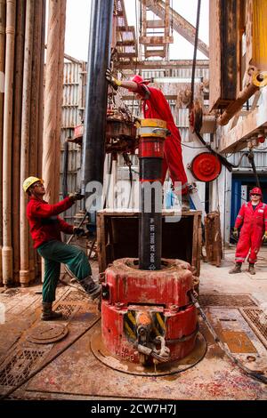 Gruppe von Ölarbeitern auf Öllagerstätte. Anschluss des Bohrrohrs. Öllagerstätte Zhaik-Munai, Kasachstan Stockfoto