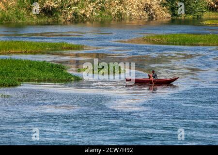 EDFU, ÄGYPTEN - 17. MÄRZ 2010 : EIN Mann rudert sein Boot vorbei Schilfinseln auf dem Nil in der Nähe von Edfu in Ägypten. Stockfoto