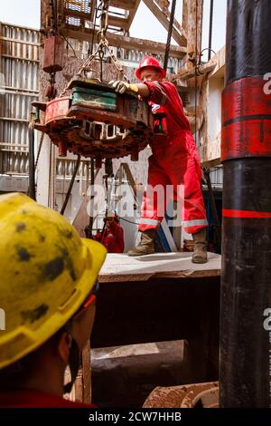 Ölablagerung. Arbeiter, der elektrische Drahtreifen zum Verbinden von Bohrrohren verwendet. Öllagerstätte Zhaik-Munai, Kasachstan. Stockfoto